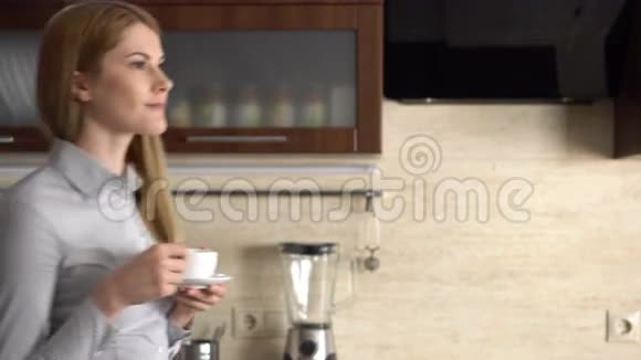 美丽的女商人站在她的厨房微笑在家开心轻松喝咖啡视频的预览图