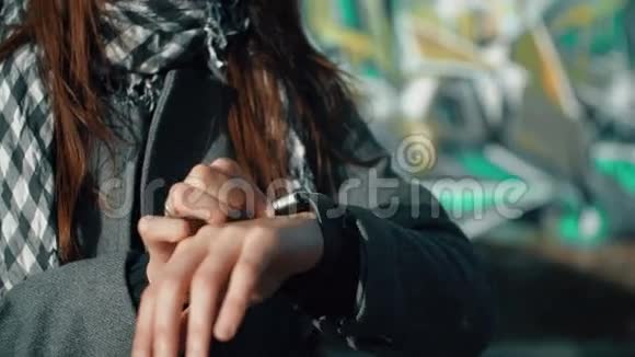 一位女士使用她的智能手表触摸屏设备在明亮的背景4k视频的预览图