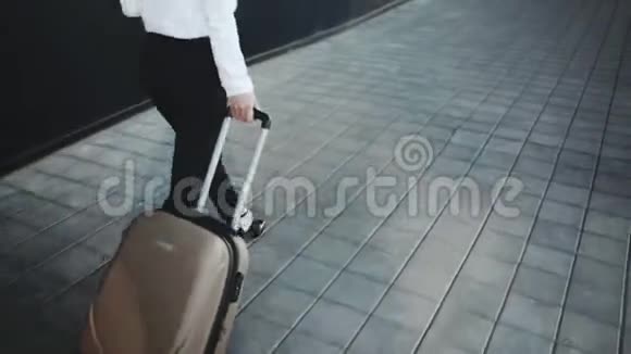 成功的女孩在行李领取区的车轮上滚动一个手提箱视频的预览图