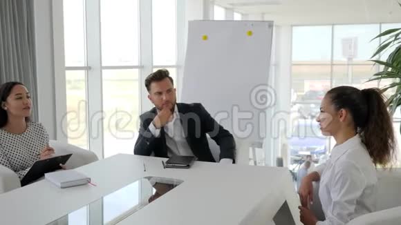 在白色宽敞的办公室里面试进入大公司的女性候选人与秘书和秘书对话视频的预览图