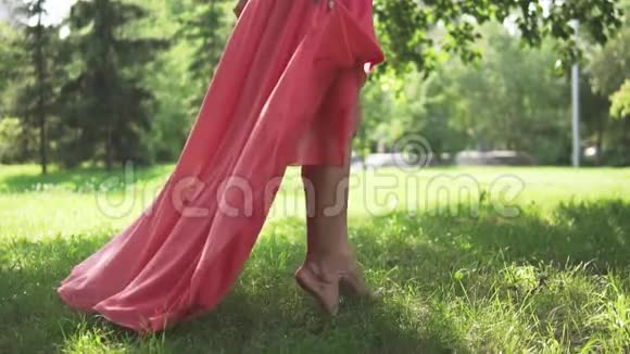 光脚双腿漂亮的少女在草地上特写穿红裙子的女孩赤脚走在草地上视频的预览图
