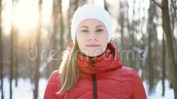 美丽的年轻女子站在冬天的公园里微笑着深吸一口气慢动作录像视频的预览图