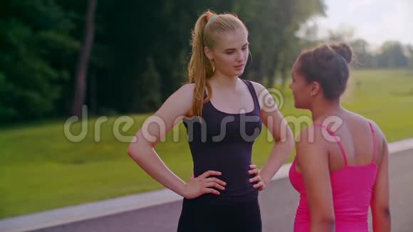 穆拉托女人和金发女孩说话夏天在公园聊天的女性朋友视频的预览图
