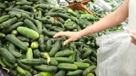 一个女人在蔬菜货架上的超市里买蔬菜和水果男人选择黄瓜慢动作视频的预览图