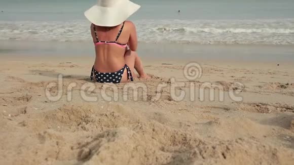 穿比基尼戴太阳帽的女人在海边晒日光浴的后景视频的预览图