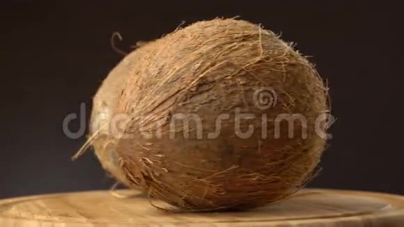 两个成熟的热带椰子在黑色背景的木桌上旋转可循环使用视频的预览图