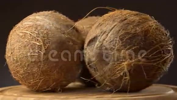 三个成熟的热带椰子在黑色背景的木桌上旋转可循环使用视频的预览图