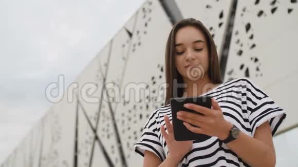 美丽的学生女孩在户外阅读电子书视频的预览图