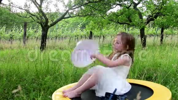 一个可爱的女孩在自然花园里休息小女孩穿白色婚纱视频的预览图