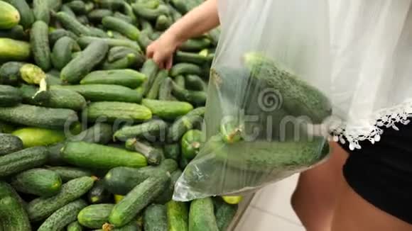 一个女人在蔬菜货架上的超市里买蔬菜和水果男人选择黄瓜慢动作视频的预览图
