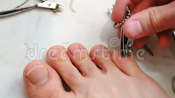 用剪刀剪脚趾甲的人男性用脚剪脚趾甲脚和脚趾特写上景视频的预览图