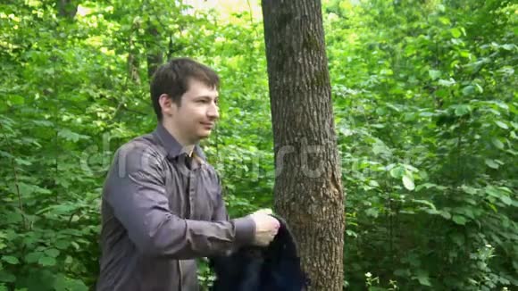 一个年轻人站在树林里把夹克扔在肩膀上自拍慢动作视频的预览图