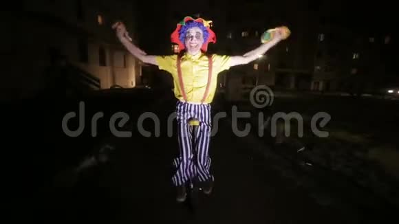 在黑暗的街道上骑着独轮车的悲伤恐怖的小丑视频的预览图