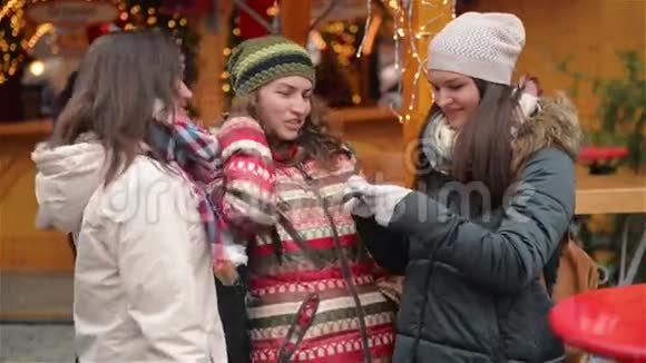三个女朋友在圣诞市场上用智能手机自拍快乐的女人在圣诞快乐的户外活动视频的预览图