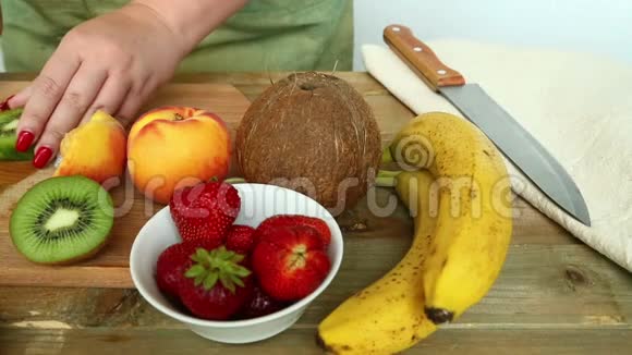 水果鸡尾酒的小板上有香蕉草莓桃子女人拿着奇异果开刀视频的预览图
