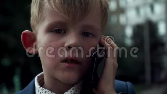 一个穿着商务服的严肃面孔在电话里说话的小男孩视频的预览图