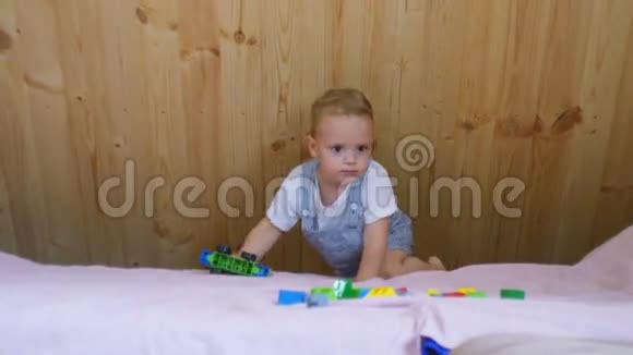 一个小男孩在阳光明媚的房间里沙发上玩他的玩具视频的预览图