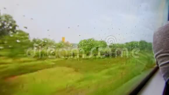 带雨滴的火车窗口提供绿色景观视频的预览图