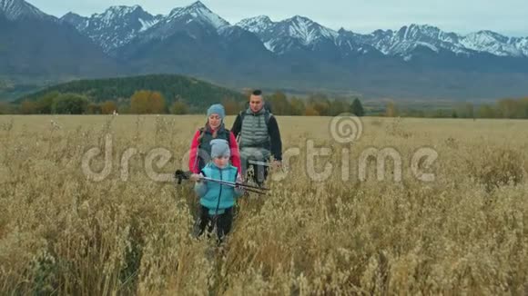 人们在麦田里走在美丽的山脉附近家庭旅行人的环境由山父母和孩子视频的预览图