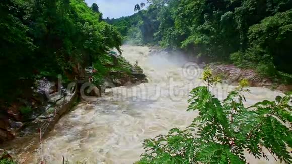 暴风山河瀑布在绿色的岩石河岸之间流动视频的预览图
