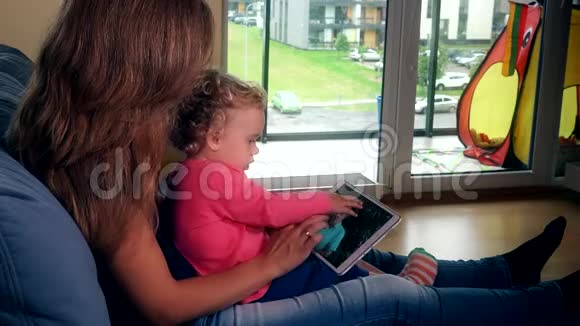 儿童与母亲一起观看平板电脑屏幕上的家庭相册视频的预览图
