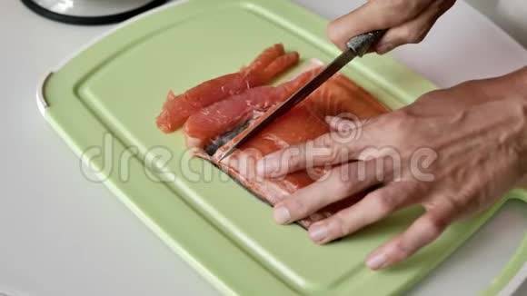 女性手用刀在浅绿色的砧板上切一片三文鱼视频的预览图