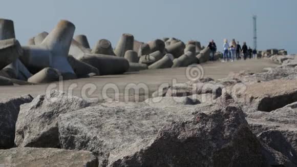 游客和游客在码头和防波堤的岩石上漫步到克拉西佩达港的入口处视频的预览图