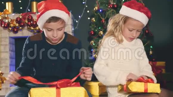 孩子们打开礼品盒靠近装饰好的圣诞树视频的预览图