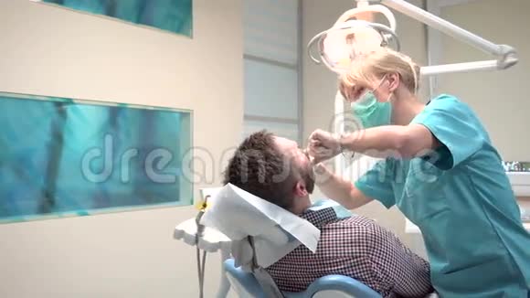 牙医检查病人的牙齿并与他交谈是的是的视频的预览图