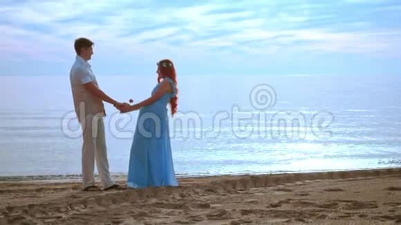 日出时两个人在海边牵手怀孕夫妇海滩视频的预览图