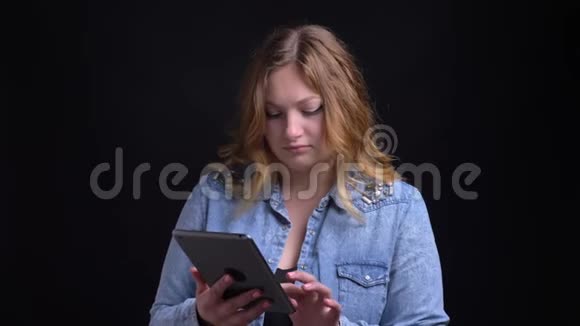 在镜头前的平板电脑上输入白种人成年金发女性的特写镜头背景是孤立的视频的预览图