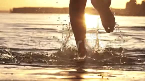 日落时在浅水中奔跑的女孩慢动作视频的预览图