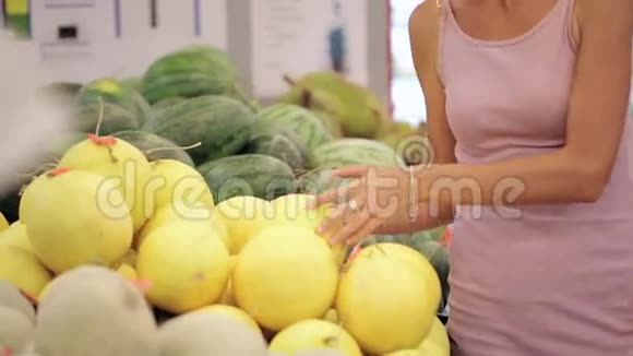 在超市挑选甜瓜的年轻女子视频的预览图