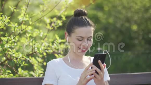 在公园用智能手机聊天的年轻女子视频的预览图