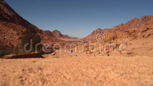 人们沿着沙漠山脉之间的道路行走视频的预览图