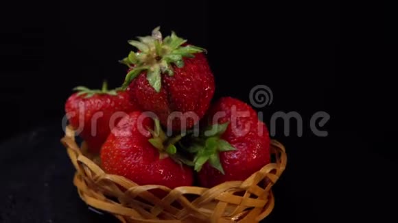 一个成熟的草莓在柳条篮子旋转在黑色的背景视频的预览图