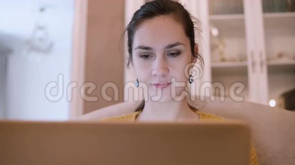 年轻女子坐在客厅的沙发上用笔记本电脑女性上网视频的预览图