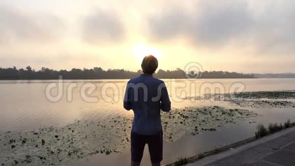 年轻人在日落的河堤上做运动视频的预览图