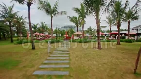 沿绿草草坪行至酒店游泳池视频的预览图