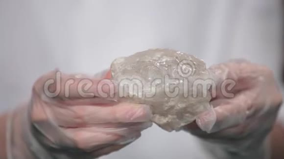 戴着白色手套的女性手拿着石头矿物晶石宏观紫色粗糙紫晶石英晶氟化物视频的预览图