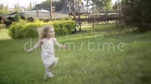 微笑的卷发小女孩跑过草地向她的母亲视频的预览图