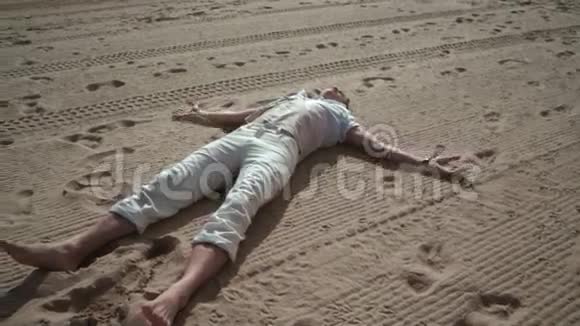 在沙滩上放松的人在沙滩上做天使的人躺在沙滩上的人视频的预览图