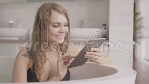 年轻女子在洗澡时使用平板电脑视频的预览图