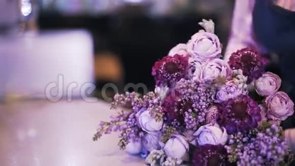 一个女人花店做紫色花束的侧视图视频的预览图