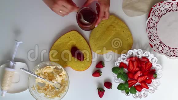一个女人把果酱放在饼干上茶托旁边是一个草莓有一个奶油视频的预览图