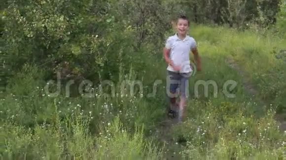 有趣的男孩沿着绿树和青草环绕的道路奔跑视频的预览图