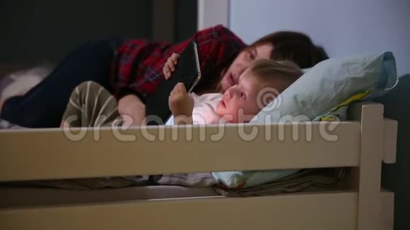 儿子和母亲在床上玩触摸垫游戏的特写镜头业余娱乐视频的预览图