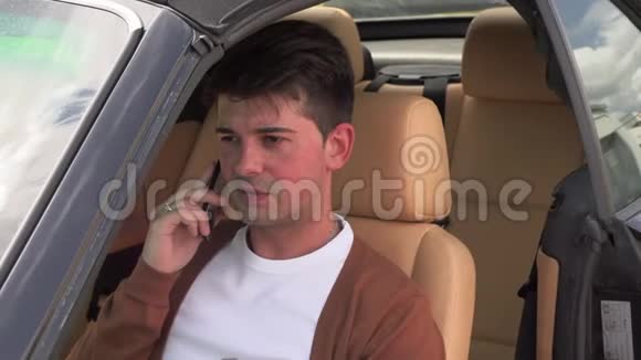 一个年轻人坐在破车里打电话视频的预览图