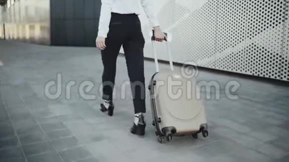 成功的女孩在行李领取区的车轮上滚动一个手提箱视频的预览图
