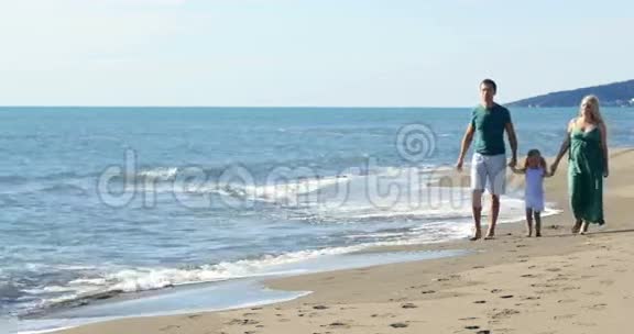 爸爸妈妈和女儿沿着海滩散步视频的预览图